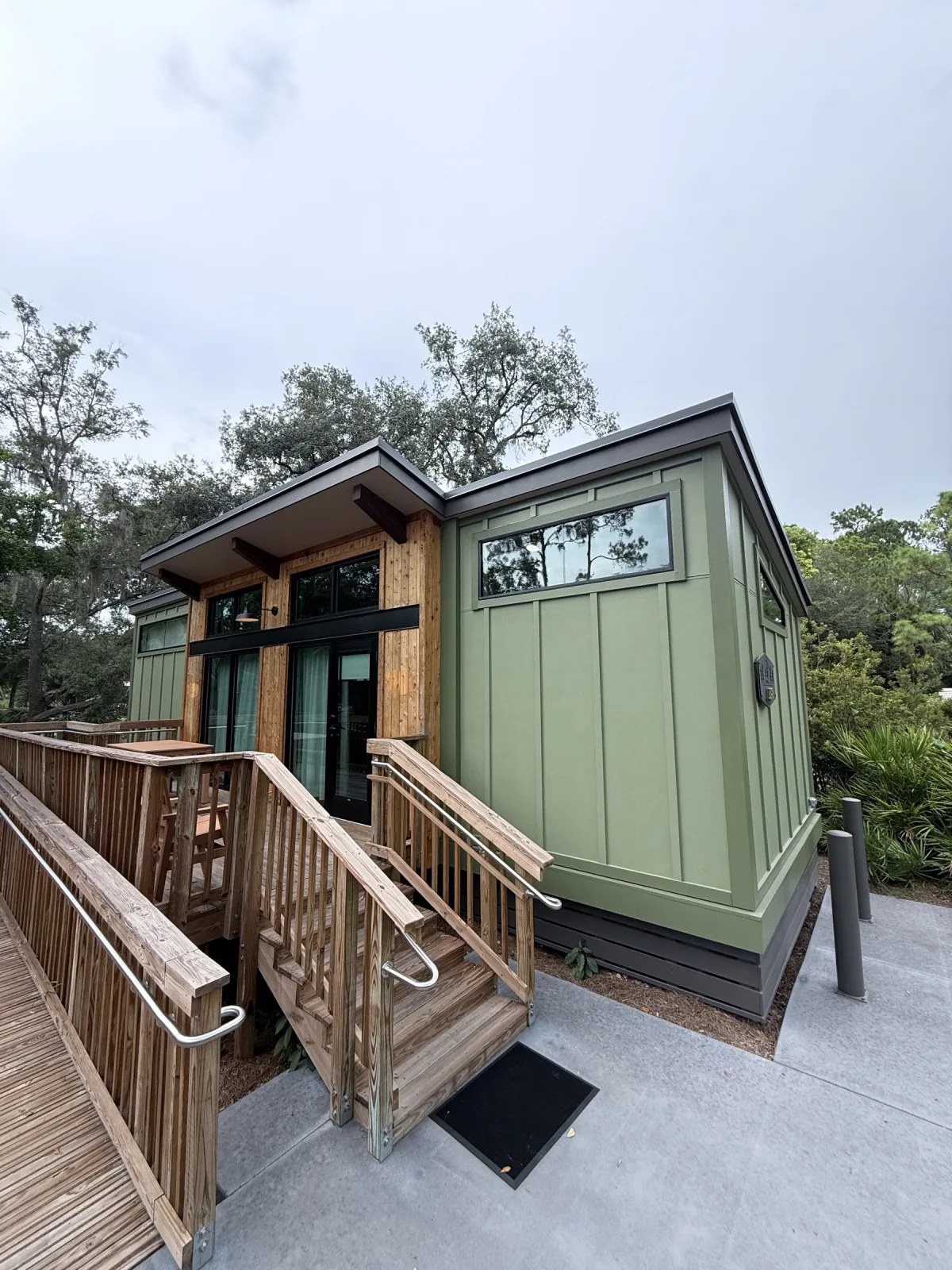 A freshly-rebuilt sage-green cabin with its private wood deck and front-door stairs — the new 2024 DVC design.