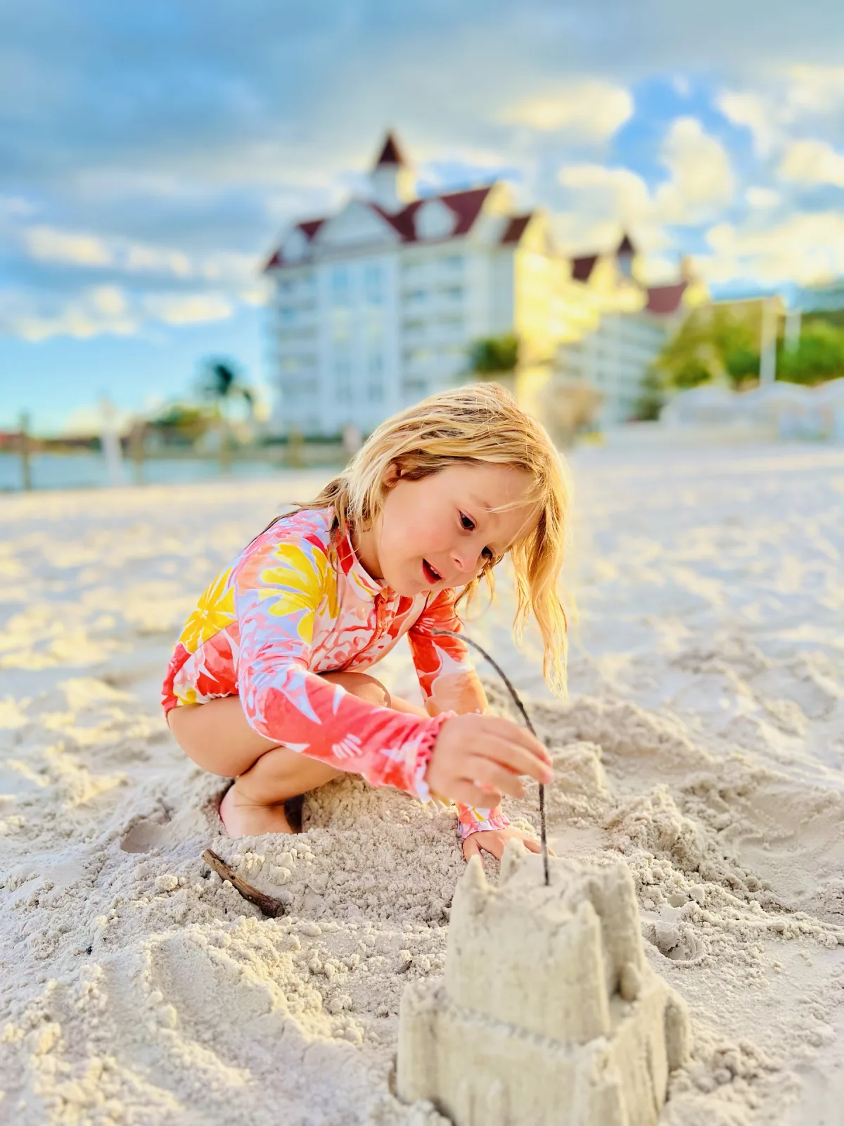 Sand-castle weather on the resort beach at golden hour — the Grand Floridian's main building looking out across the Seven Seas Lagoon.
