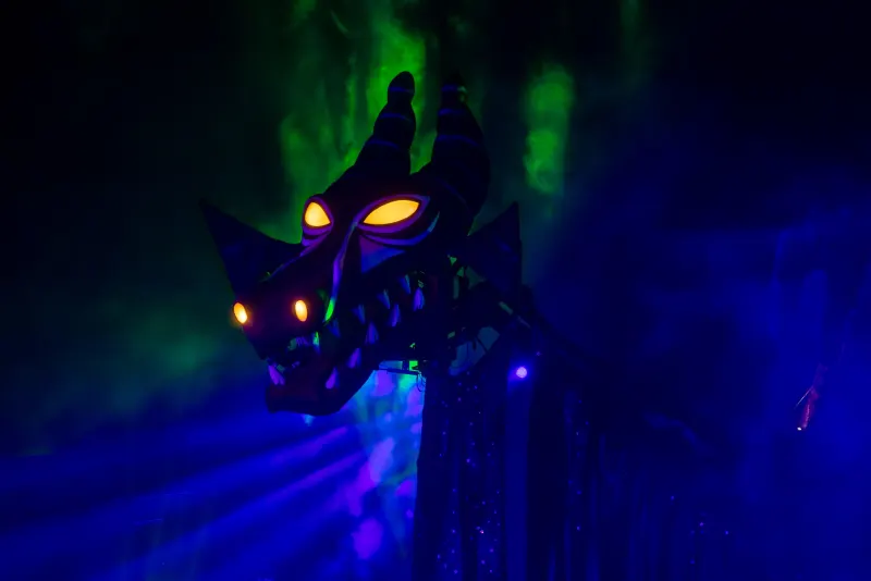 Maleficent's dragon appears for the villains sequence — green smoke, glowing eyes, taller than the stage.