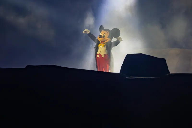 The closing tableau — Mickey lit by the boat-mounted spotlight on the lagoon.